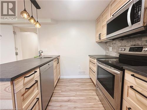 Kitchen featuring sink, decorative backsplash, light brown cabinetry, decorative light fixtures, and stainless steel appliances - 20 Pintail Place, Cambridge, ON 