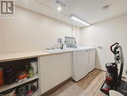 Washroom with washer and clothes dryer, sink, and light hardwood / wood-style floors - 