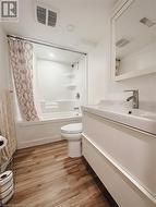 Full bathroom with hardwood / wood-style flooring, vanity, toilet, and shower / tub combo - 