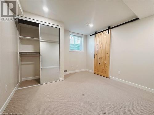 Unfurnished bedroom featuring light carpet, a barn door, and a closet - 20 Pintail Place, Cambridge, ON 