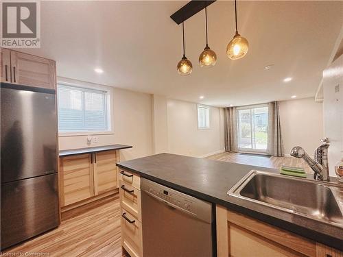 Kitchen featuring decorative light fixtures, light hardwood / wood-style floors, sink, and appliances with stainless steel finishes - 20 Pintail Place, Cambridge, ON 