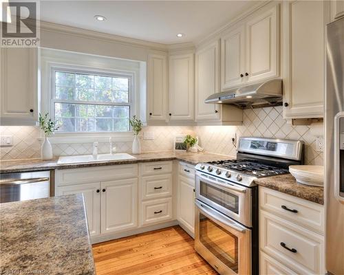 Kitchen featuring sink, decorative backsplash, light wood-type flooring, appliances with stainless steel finishes, and white cabinetry - 147 Dalewood Drive, Kitchener, ON 