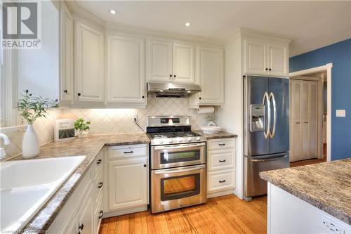 Kitchen featuring appliances with stainless steel finishes, light wood-type flooring, backsplash, sink, and white cabinets - 147 Dalewood Drive, Kitchener, ON 