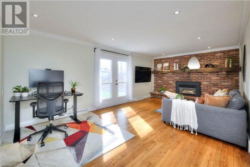 Living room with a brick fireplace, ornamental molding, french doors, and light hardwood / wood-style flooring - 147 Dalewood Drive, Kitchener, ON 