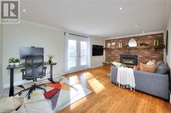 Living room with a brick fireplace, ornamental molding, french doors, and light hardwood / wood-style flooring - 