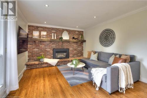 Living room featuring a fireplace, ornamental molding, and light wood-type flooring - 147 Dalewood Drive, Kitchener, ON 