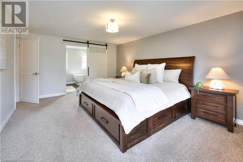 Bedroom with a barn door, ensuite bathroom, and light colored carpet - 147 Dalewood Drive, Kitchener, ON 