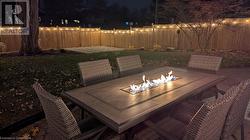 Patio at night featuring a fire pit and a lawn - 