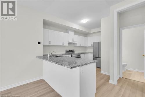 Kitchen featuring white cabinets, light wood-type flooring, and appliances with stainless steel finishes - 677 Park Road N Unit# 147, Brantford, ON 