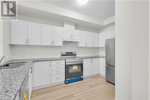 Kitchen with appliances with stainless steel finishes, white cabinetry, light hardwood / wood-style flooring, and sink - 677 Park Road N Unit# 147, Brantford, ON 