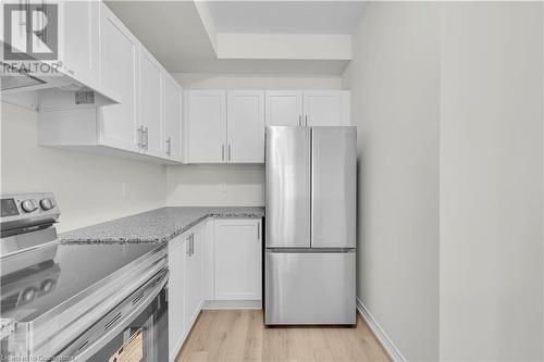 Kitchen with light stone counters, light wood-type flooring, white cabinetry, and stainless steel appliances - 677 Park Road N Unit# 147, Brantford, ON 