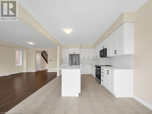 Kitchen with backsplash, appliances with stainless steel finishes, a center island with sink, white cabinets, and light wood-type flooring - 126 Broadacre Drive, Kitchener, ON 