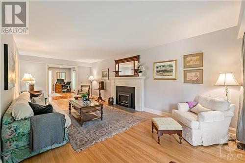 Large living room featuring oak hardwood floors and remote controlled gas fireplace - 10 Riverbrook Road, Ottawa, ON 