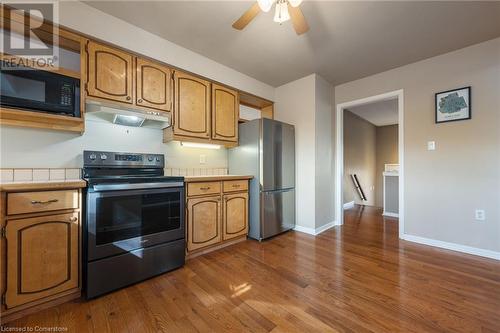 Kitchen featuring ceiling fan, dark wood-type flooring, and appliances with stainless steel finishes - 118 Oak Street, Simcoe, ON 