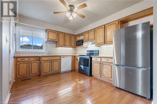 Kitchen with stainless steel refrigerator, ceiling fan, range with electric stovetop, white dishwasher, and light hardwood / wood-style floors - 118 Oak Street, Simcoe, ON 