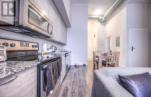 Kitchen featuring electric panel, light stone counters, dark wood-type flooring, and appliances with stainless steel finishes - 253 Albert Street N Unit# 104, Waterloo, ON - Indoor Photo Showing Kitchen