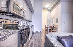 Kitchen featuring electric panel, light stone counters, dark wood-type flooring, and appliances with stainless steel finishes - 