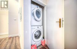 Clothes washing area with hardwood / wood-style floors and stacked washer / dryer - 