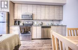 Kitchen featuring dark hardwood / wood-style flooring, stainless steel appliances, and stone counters - 