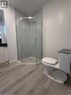 Bathroom with hardwood / wood-style flooring, toilet, and a shower with shower door - 