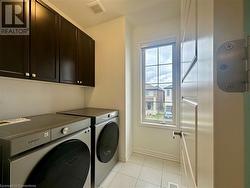 Laundry room with cabinets, light tile patterned floors, and washing machine and clothes dryer - 