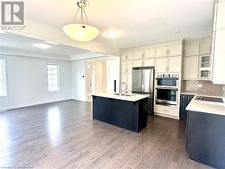 Kitchen featuring sink, appliances with stainless steel finishes, decorative light fixtures, a kitchen island, and dark hardwood / wood-style flooring - 