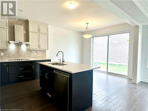 Kitchen featuring stainless steel dishwasher, wall chimney exhaust hood, sink, white cabinetry, and an island with sink - 94 Milt Schmidt Street, Kitchener, ON - Indoor Photo Showing Kitchen With Double Sink With Upgraded Kitchen