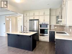 Kitchen with stainless steel appliances, dark hardwood / wood-style floors, a center island with sink, and sink - 