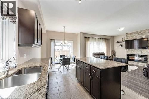 Kitchen with a center island, sink, a stone fireplace, light stone counters, and a breakfast bar area - 243 Greenwater Place Unit# Upper, Kitchener, ON - Indoor Photo Showing Kitchen With Fireplace With Double Sink