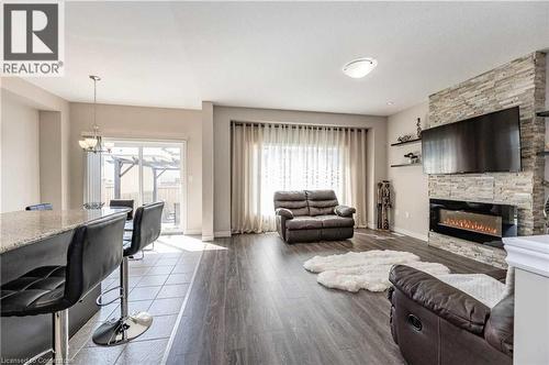 Living room featuring a stone fireplace, a chandelier, and dark wood-type flooring - 243 Greenwater Place Unit# Upper, Kitchener, ON - Indoor Photo Showing Living Room With Fireplace