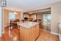 Kitchen with a center island, light brown cabinets, light wood-type flooring, decorative light fixtures, and a chandelier - 