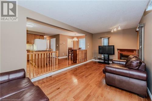 Living room with a textured ceiling, light hardwood / wood-style floors, rail lighting, and a notable chandelier - 435 Shadow Wood Crescent, Waterloo, ON - Indoor Photo Showing Living Room