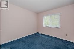 Unfurnished room featuring dark colored carpet - 