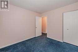 Unfurnished bedroom with a closet and dark colored carpet - 