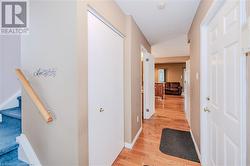 Hallway with vaulted ceiling, a textured ceiling, and light hardwood / wood-style flooring - 