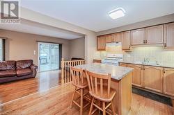 Kitchen with a breakfast bar, white gas stove, a kitchen island, and light hardwood / wood-style flooring - 