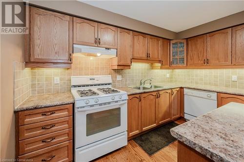 Kitchen with light wood-type flooring, backsplash, light stone counters, white appliances, and sink - 435 Shadow Wood Crescent, Waterloo, ON - Indoor Photo Showing Kitchen With Double Sink