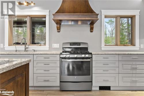 Kitchen featuring premium range hood, light stone counters, stainless steel gas stove, and a healthy amount of sunlight - 3298 Seydel Lane Lane, Coldwater, ON - Indoor Photo Showing Kitchen