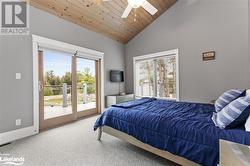 Bedroom featuring ceiling fan, wood ceiling, access to outside, and multiple windows - 