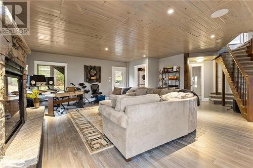 Living room featuring a stone fireplace, light hardwood / wood-style flooring, and wooden ceiling - 3298 Seydel Lane Lane, Coldwater, ON - Indoor Photo Showing Living Room