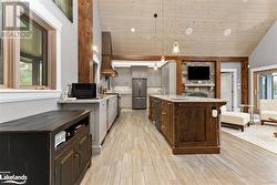 Kitchen with wooden ceiling, lofted ceiling, light hardwood / wood-style flooring, decorative light fixtures, and stainless steel appliances - 