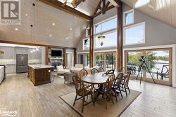 Dining space with beam ceiling, sink, high vaulted ceiling, and light hardwood / wood-style flooring - 