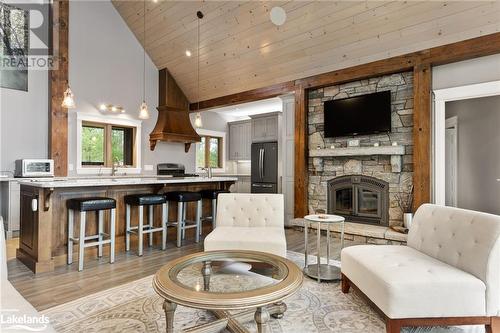 Living room featuring a stone fireplace, high vaulted ceiling, wooden ceiling, and light wood-type flooring - 3298 Seydel Lane Lane, Coldwater, ON - Indoor With Fireplace