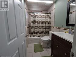 Full bathroom with tile patterned floors, vanity, shower / tub combo with curtain, tile walls, and toilet - 