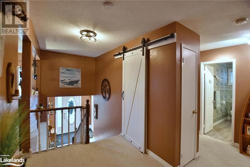 Hallway featuring a textured ceiling, a barn door, and light carpet - 97 Glen Eton Road, Wasaga Beach, ON 