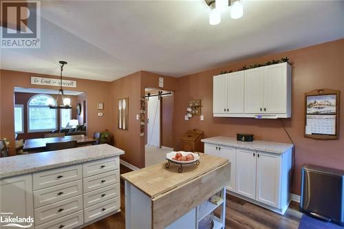 Kitchen with light stone counters, dark wood-type flooring, pendant lighting, a barn door, and white cabinetry - 97 Glen Eton Road, Wasaga Beach, ON 