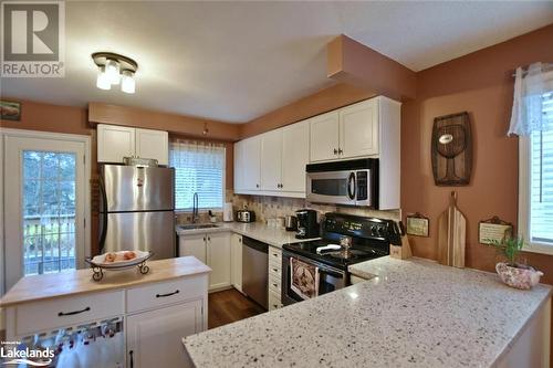 Kitchen featuring dark hardwood / wood-style flooring, white cabinetry, sink, and stainless steel appliances - 97 Glen Eton Road, Wasaga Beach, ON 