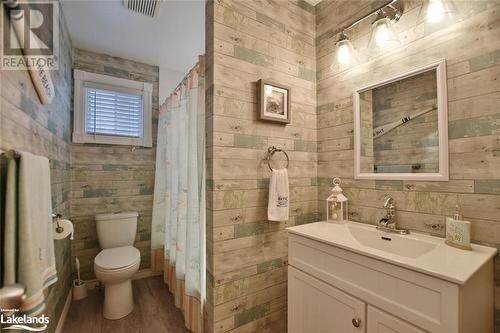 Bathroom featuring vanity, wooden walls, hardwood / wood-style flooring, a shower with shower curtain, and toilet - 97 Glen Eton Road, Wasaga Beach, ON 