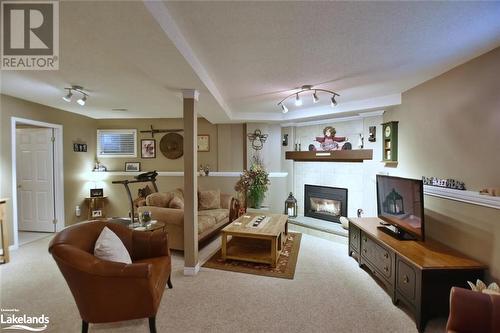 Living room with a fireplace, a textured ceiling, light colored carpet, and track lighting - 97 Glen Eton Road, Wasaga Beach, ON 