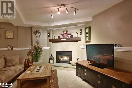 Living room featuring a raised ceiling, a textured ceiling, track lighting, a fireplace, and carpet - 97 Glen Eton Road, Wasaga Beach, ON 